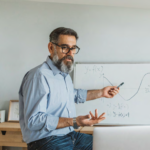 middle age man with glasses teaching with white board and laptop