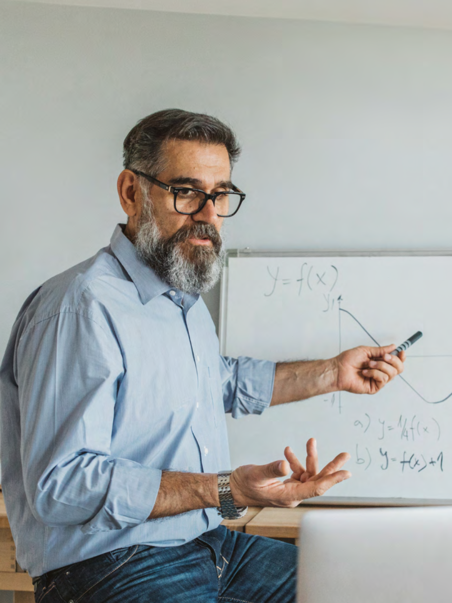 middle age man with glasses teaching with white board and laptop